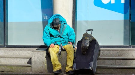 Homeless man sitting in front of a building