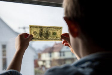 Boy holding dollar near window