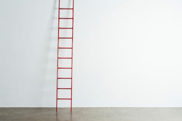 Ladder leaning against white wall.