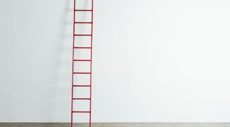 Ladder leaning against white wall.